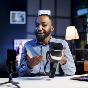 Tech content creator filming technology review of newly launched futuristic VR glasses, trying them and giving his impressions to audience. Internet star probing virtual reality device